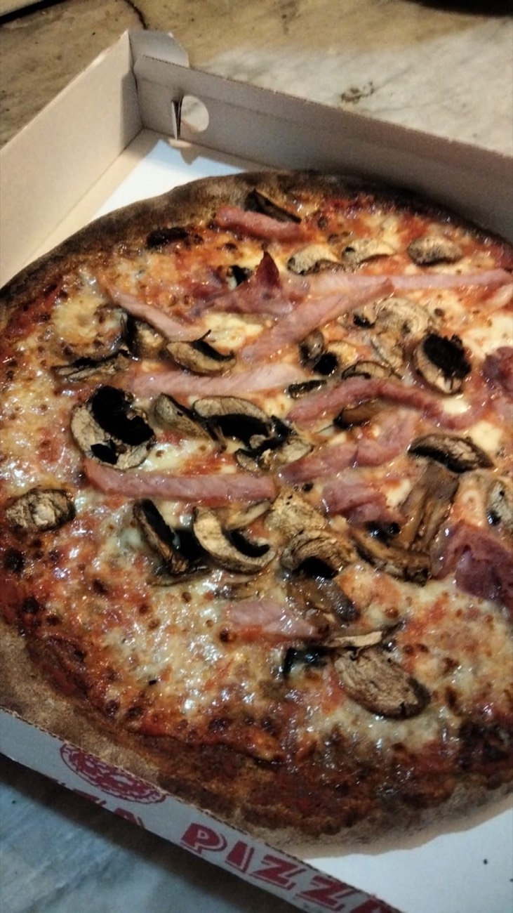 Pizza con funghi e prosciutto cotto nel cartone d'asporto