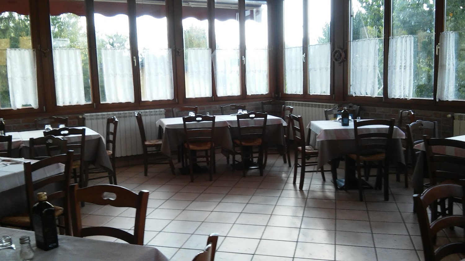 La sala del ristorante con la veranda luminosa affacciata sul verde